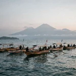 Bateaux traditionnels balinais sur la mer calme à l'aube à Lovina Beach, Bali, avec des collines volcaniques dans la brume en arrière-plan