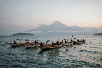 Bateaux traditionnels balinais sur la mer calme à l'aube à Lovina Beach, Bali, avec des collines volcaniques dans la brume en arrière-plan
