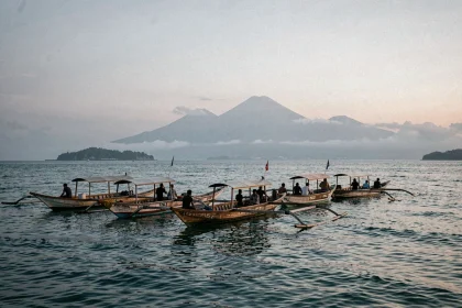 Bateaux traditionnels balinais sur la mer calme à l'aube à Lovina Beach, Bali, avec des collines volcaniques dans la brume en arrière-plan