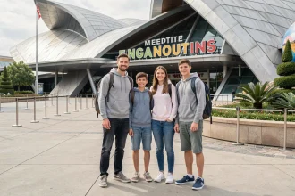Famille souriante à l'entrée du Parc Walt Disney Studios, prête pour une journée d'attractions