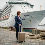 Voyageuse tirant sa valise sur le quai du port du Havre face à un paquebot de croisière MSC