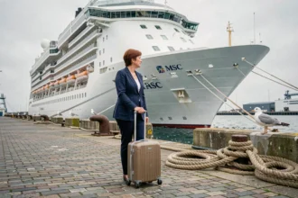 Voyageuse tirant sa valise sur le quai du port du Havre face à un paquebot de croisière MSC