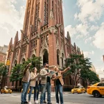 Façade extérieure du Woolworth Building à Manhattan avec des touristes consultant un guide touristique sur le trottoir de Broadway