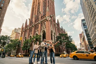 Façade extérieure du Woolworth Building à Manhattan avec des touristes consultant un guide touristique sur le trottoir de Broadway
